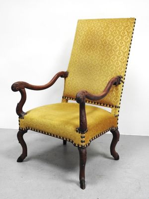 une chaise jaune posée sur un sol en béton, près d'un mur