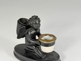 statue of a cupid holding a cup of coffee on a stand
