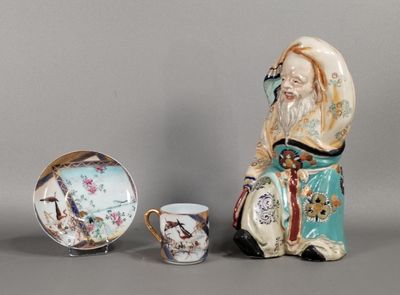 une figurine représentant un homme tenant une tasse et une soucoupe à côté d'une assiette sur laquelle est représenté un oiseau