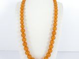 a close up of an orange beaded necklace on a mannequin