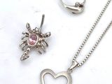 silver necklace, ring, and pendant with a heart and a spider