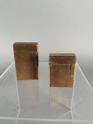 pair of gold tone cigarette lighters on clear acrylic stand
