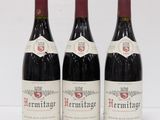 three bottles of red wine sitting on top of a white table