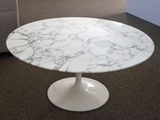 a white marble table with a white base on the floor