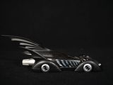 a toy car with a batmobile on top of it on a black surface