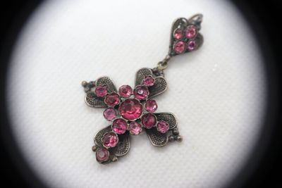 an image of a close up of a cross with pink stones