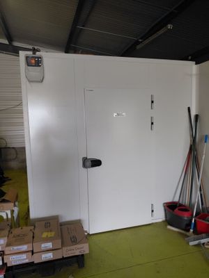 une porte blanche dans une pièce où se trouvent des cartons et des balais