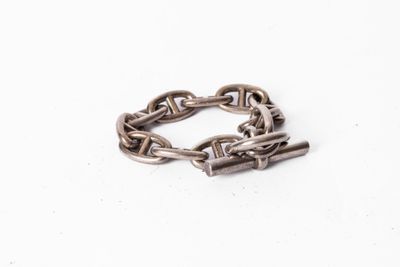 un gros plan d'un bracelet à maillons métalliques posé sur une surface blanche