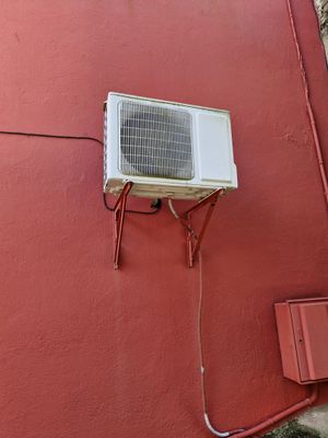 un petit climatiseur fixé sur le mur latéral d'un immeuble