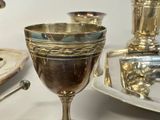 a silver goblet sitting on a table next to a silver plate