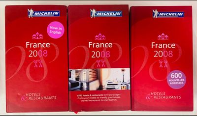 trois livres rouges sont empilés les uns sur les autres sur une table
