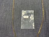 un collier à chaîne en or, avec un sac en plastique transparent en arrière-plan