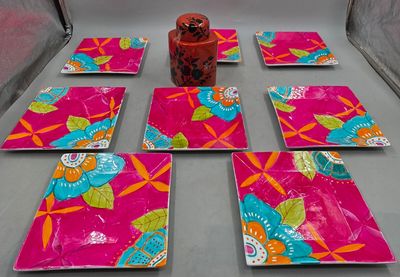 six pink plates with colorful flowers and leaves on them on a table