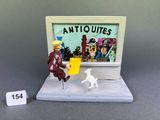 une image représentant une figurine miniature d'un homme et d'un chien devant un téléviseur