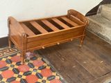a small wooden bed sitting on the floor in the corner of a room