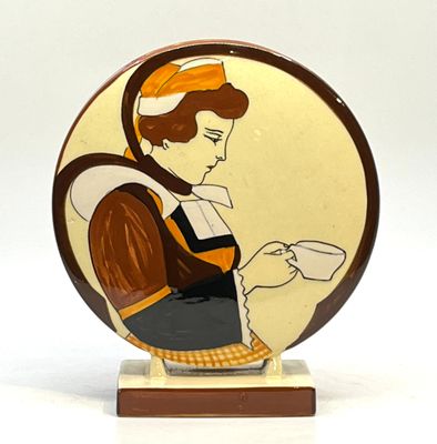 une photo d'une assiette en céramique sur laquelle figure une femme tenant une tasse