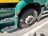 a green semi truck with a yellow stripe parked on the side of the road