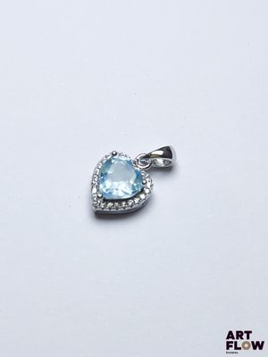une image représentant un pendentif en forme de cœur en topaze bleue, orné de diamants, sur fond blanc