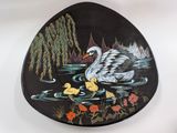 a black plate with a painting of a swan and ducklings on it