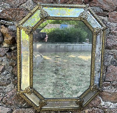 une image représentant un miroir accroché à un mur de pierre dans un jardin
