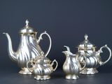 two silver teapots and a coffee pot on a table