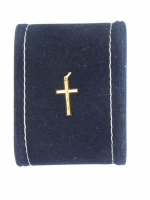 une petite croix en or posée sur un écrin en velours bleu