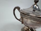 a silver cup with a lid on a silver plate