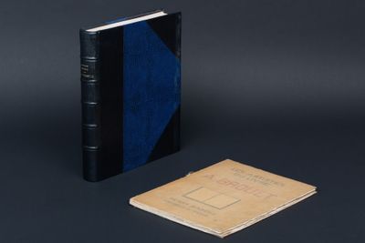 un vieux livre posé à côté d'un petit carnet sur une surface noire