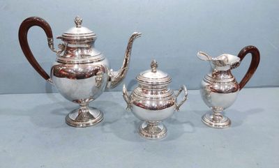 trois théières en argent et une théière posées sur une table