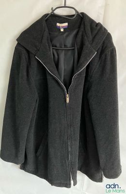 une veste noire à capuche et à fermetures éclair, suspendue à un cintre accroché au mur