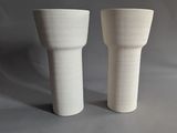 two white vases sitting next to each other on a table