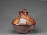 a brown vase sitting on top of a table next to a gray wall