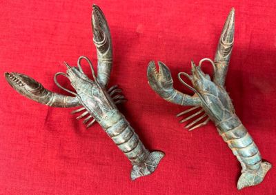 pair of silver lobster hair combs on a red cloth