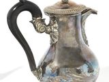 a silver coffee pot with a black handle on a white surface