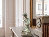 une statue représentant une femme assise sur une table en marbre