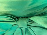 a close up photo of a green dress with a large bow