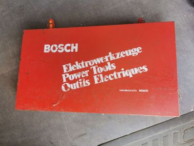 an old red box sitting on top of a table next to a metal object