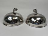 two silver plated dishes with a bird on top of them