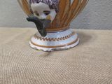 a small vase with a bird on it sitting on a table
