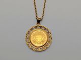 a close up of a gold coin on a chain on a table