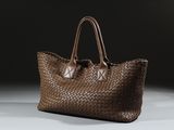 un gros plan d'un sac tissé marron posé sur une surface blanche
