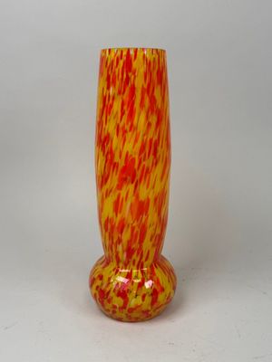 a red and yellow vase sitting on a white surface