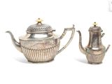 two silver teapots sitting next to each other on a white surface