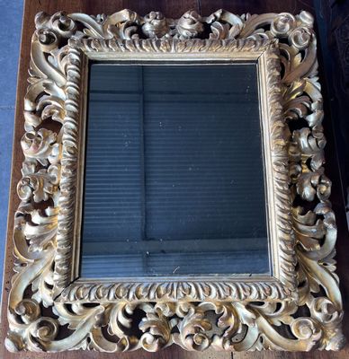 un miroir au cadre doré ouvragé posé sur une table en bois dans une pièce