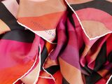a close up of a scarf with a pink, orange and black design