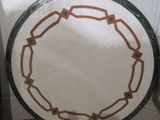 a white plate with a brown border sitting on the floor