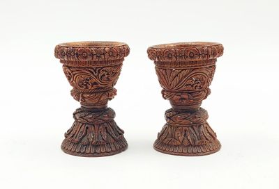 deux vases en bois posés l'un à côté de l'autre sur une surface blanche