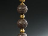 une image représentant une lampe dorée et noire surmontée de trois boules