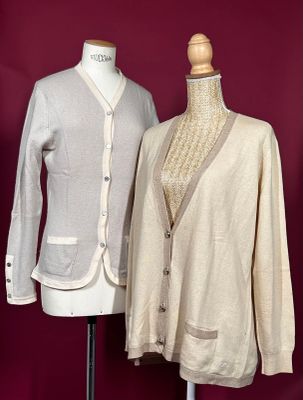two women ' s sweaters on a mannequin stand against a red wall