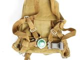un sac à dos beige contenant une tétine verte